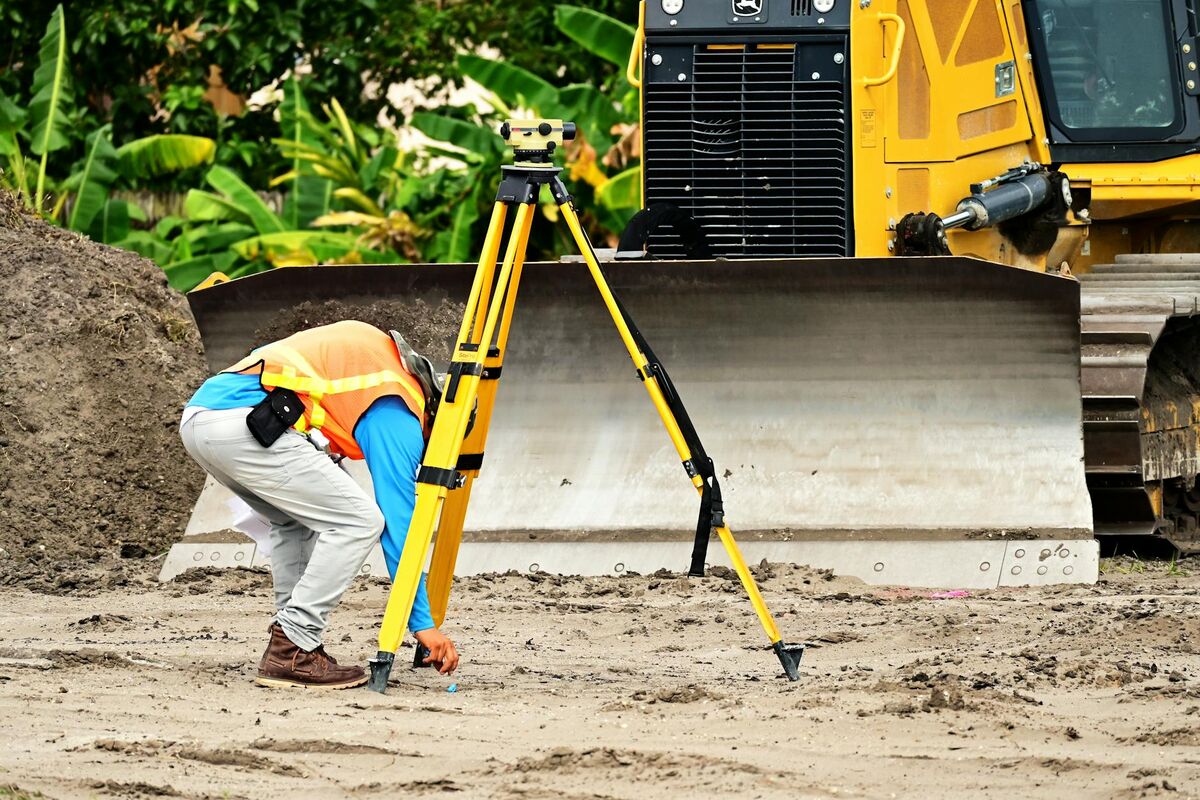 Construction worker operating a total station on an active job site