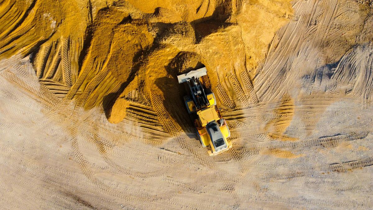 Drone aerial view of an excavator working on sand mounds at an earthwork construction site for cut and fill mapping