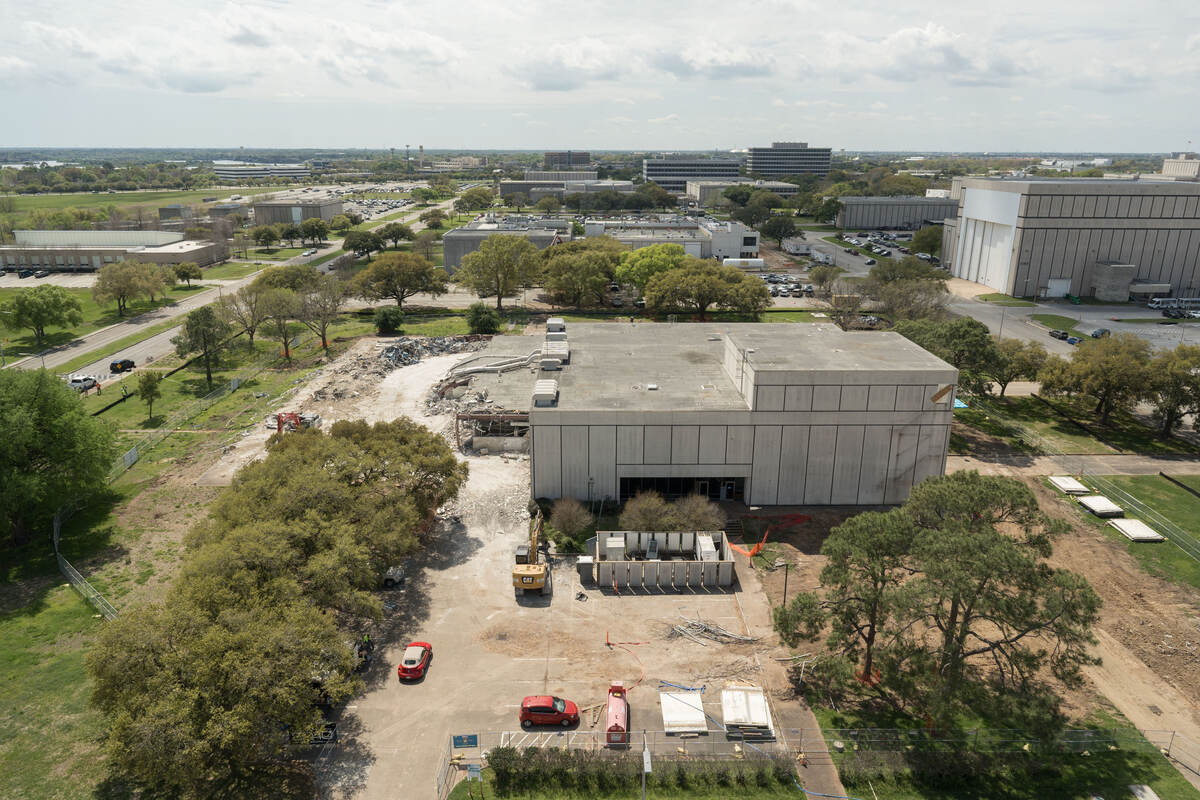 Aerial drone view of a commercial building from above showing roof and surrounding grounds