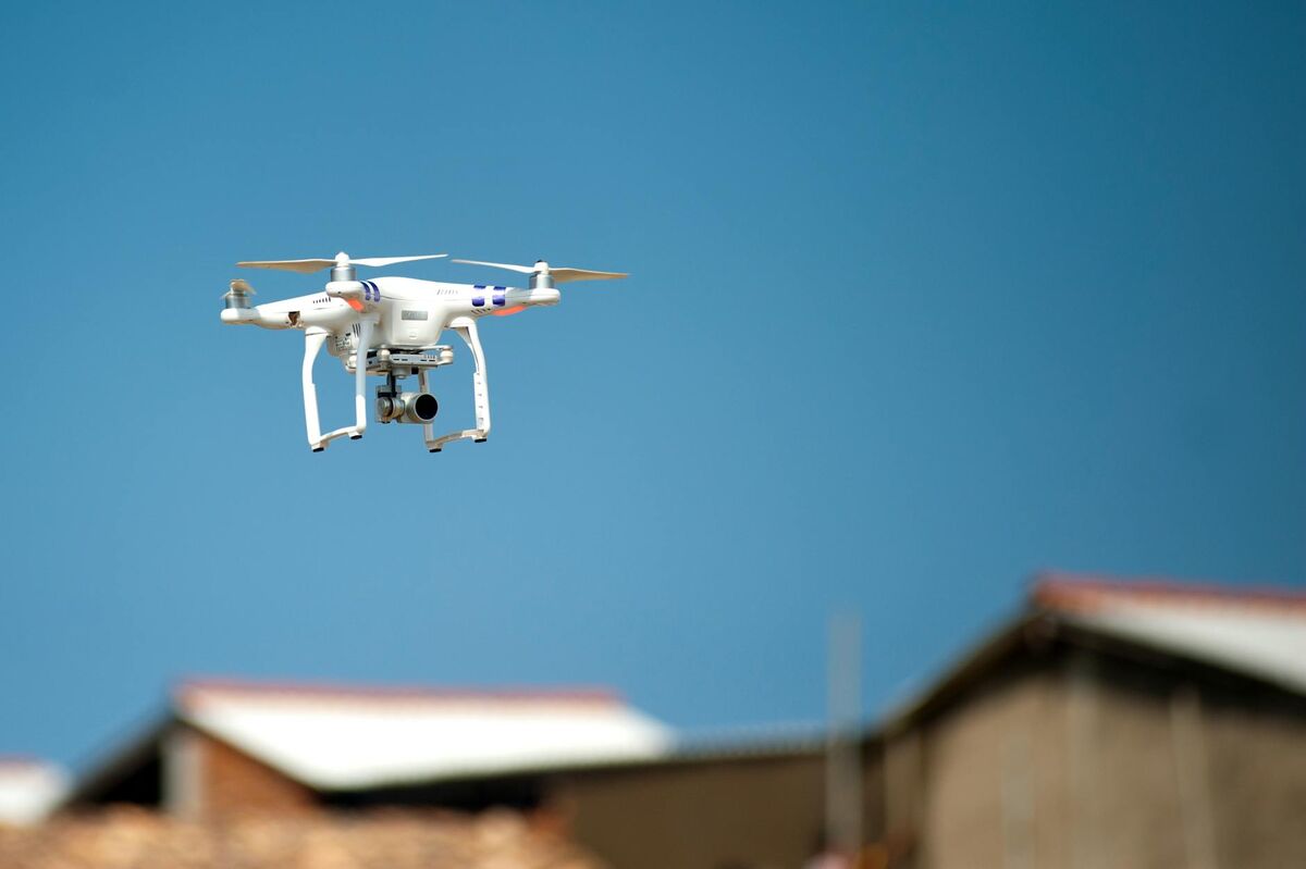 Drone with camera hovering over rooftops for commercial aerial photography work
