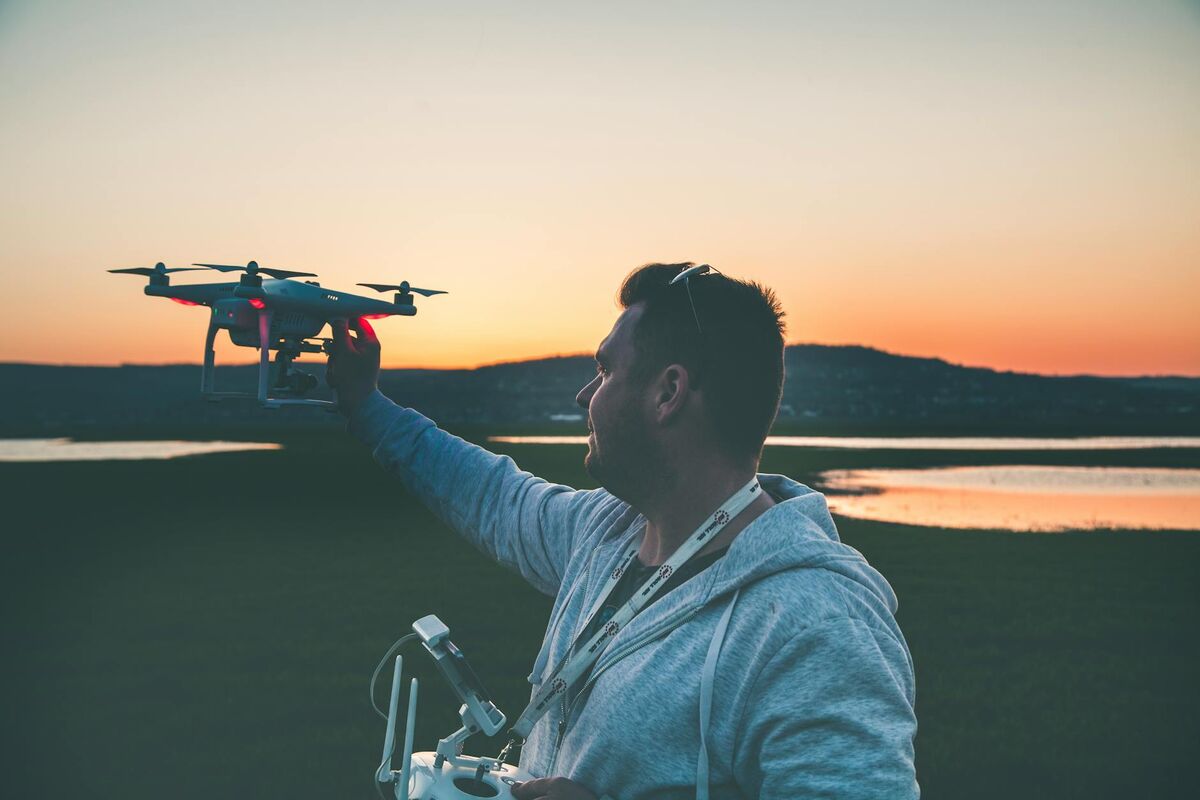 Drone operator holding a DJI drone during a professional field operation at sunset