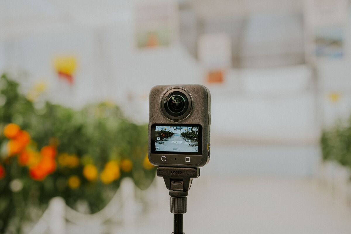 Person holding a 360 camera outdoors, ready to capture a virtual tour