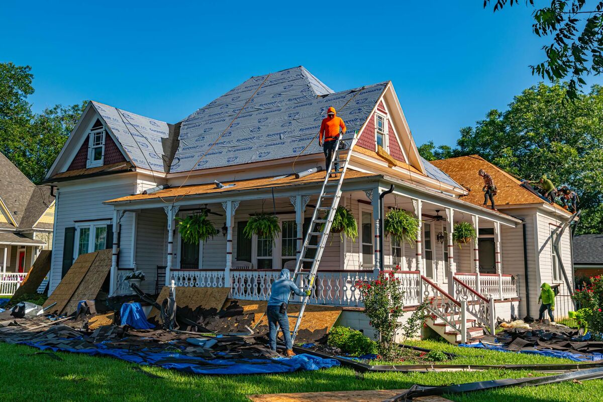 Roofers replacing the roof of a historic home, showing typical roofing contractor work