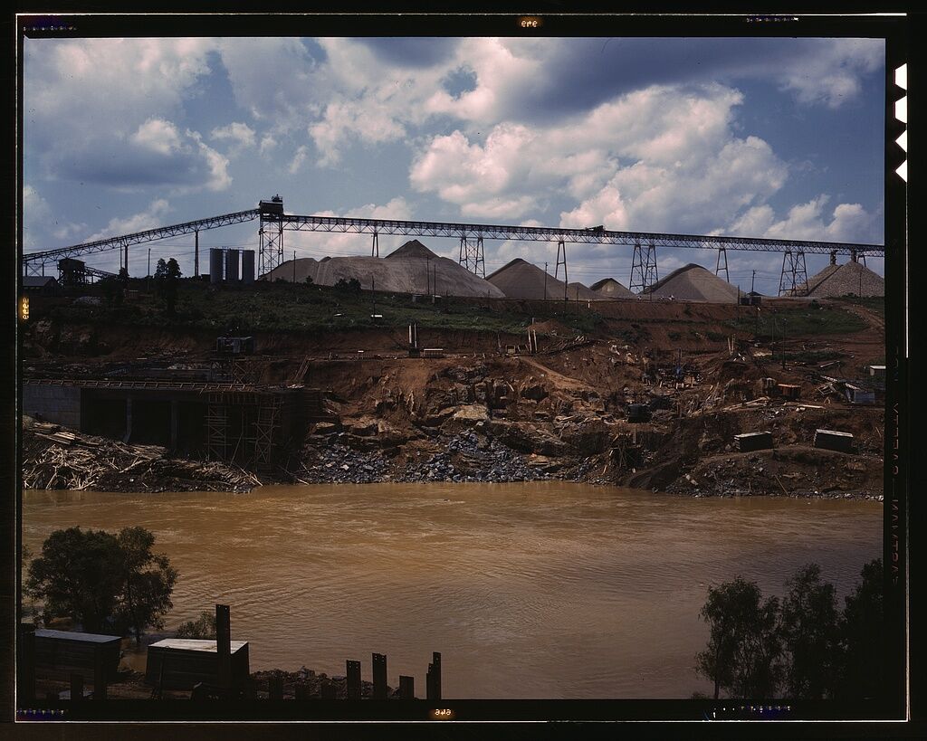 Historic aggregate storage pile at a dam construction site showing bulk material stockpile